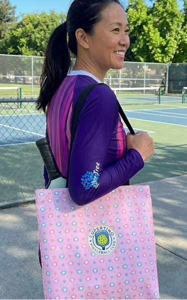 Woman holding a pickleball paddle bag walking to the court